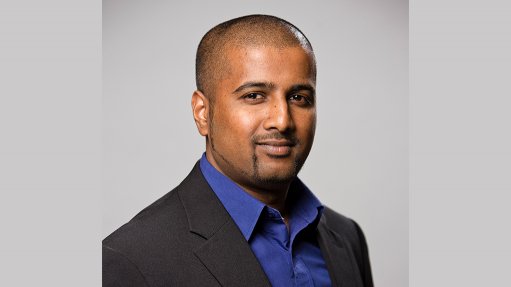 An image depicting a smiling man, Devan Reddy, wearing a suit