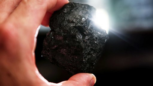 Image shows a hand holding coal