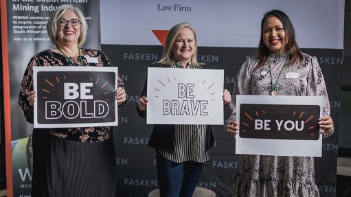 An image depicting three women from Women in Mining holding up signs that read: be bold, be brave, be you