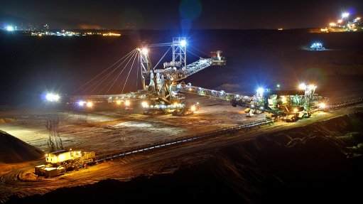 A large open pit operation at night being lit up with flood lights and masts
