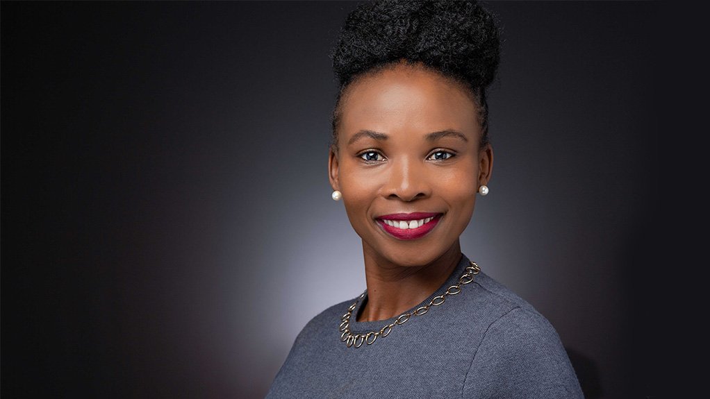 Women with red lipstick smiling, grey dress, hair up.