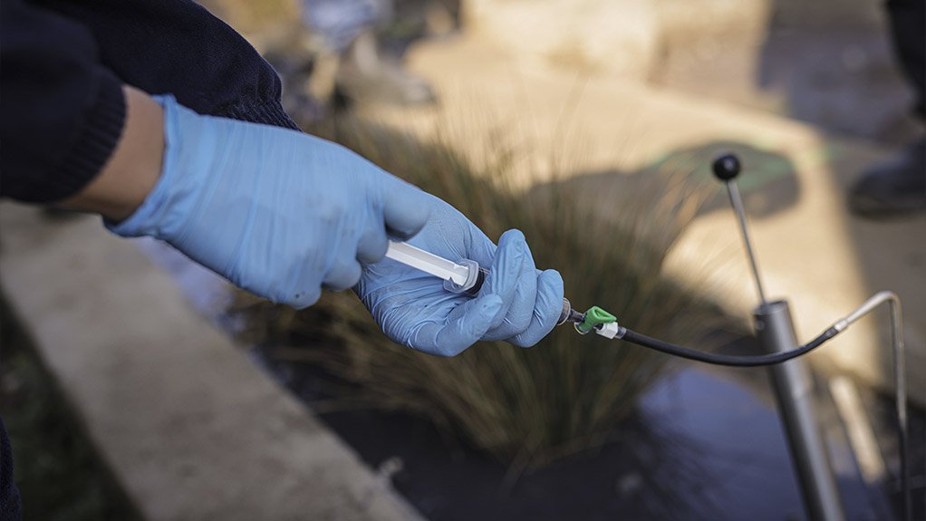 An image of a student testing the water in the constructed wetland 

