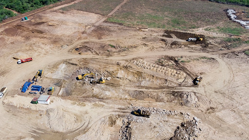 Mine site under construction with exposed ground, earthmoving equipment.