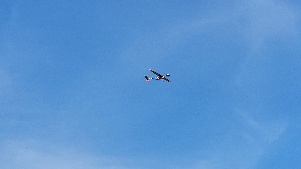 Drone flying on clear day, blue sky.