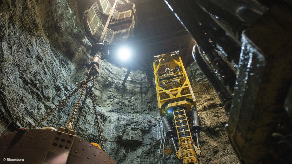 a vertical view of the shaft at the Lucara Diamond Karowe mine in Botsawana with a man in a elevator bucket looking down at the camera man