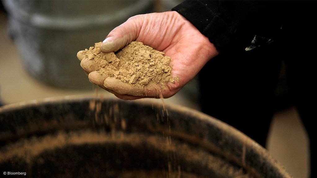 Image shows a hand holding rare earth ore 