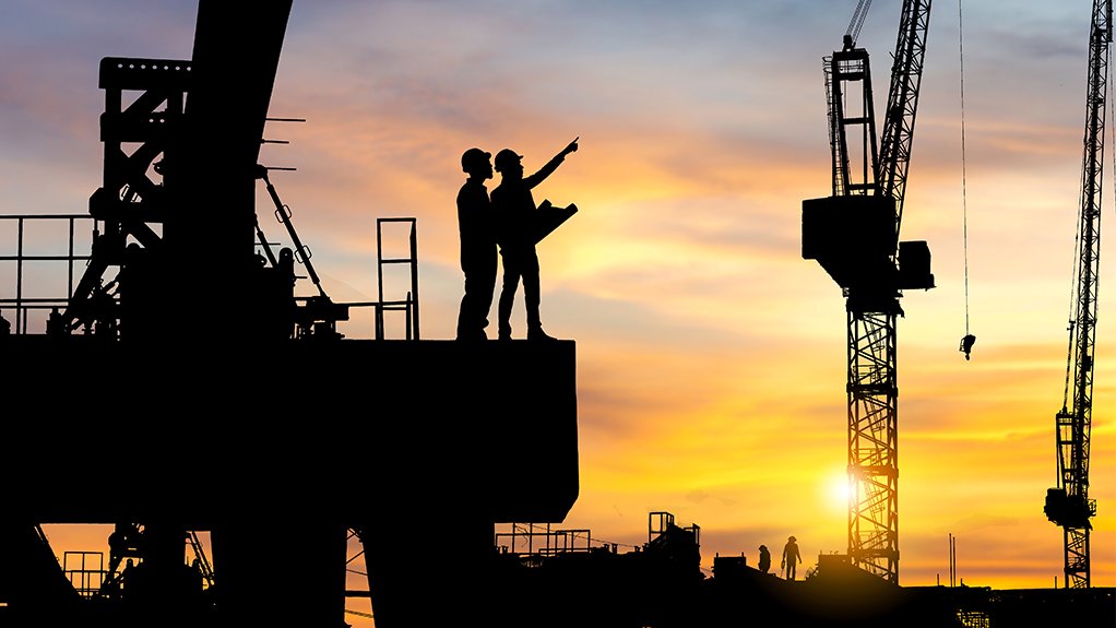 An image of a building site with the silhouette of site workers against a sunset