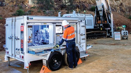 A Truscan machine which uses high-resolution sample scanning and x-ray fluorescence to better asses ores, being manned by a male technician in PPE