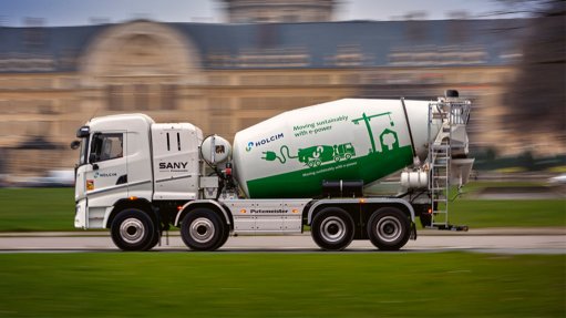 A Large white electric concrete mixer with the SANY Logo and green detailing with the Paris landscape in the backdrop