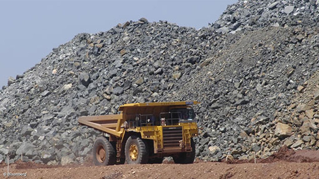 Image shows a dump truck with ore stockpiles