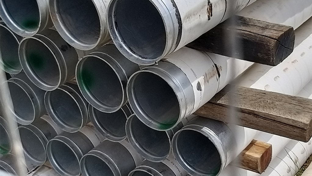 A pile of pipes behind a fence covered in a Denso Ultraflex 1250 tape, a specially formulated anti-corrosion system.