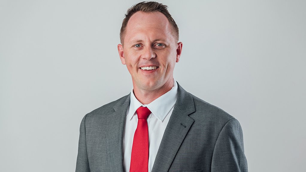 Phillip Steyn in grey suit and red tie, smiling