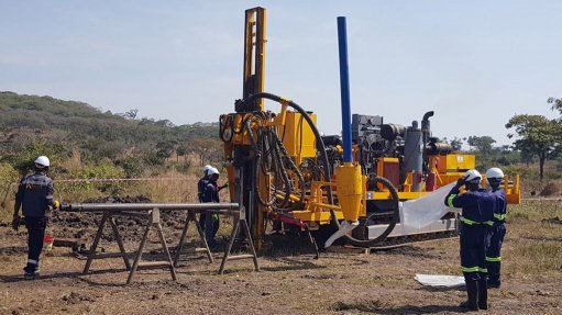 A group of men in PPE stood around a drill rig that is doing core drilling for Resources Mining Corporation's Liparamba nickel project in Tanzania