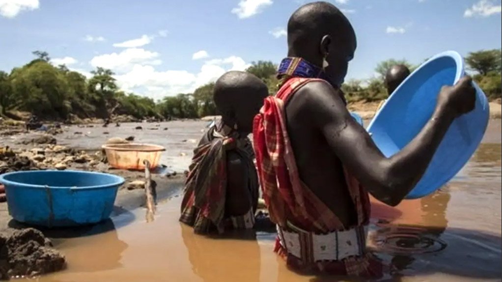 Two men standing waist deep in murky brown water panning for gold in the South Sudan mining sector
