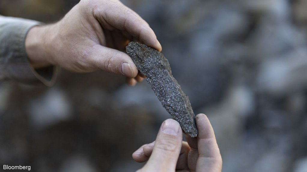 A worker inspects at a shard of graphite ore at a mine in Saint-Michel-des-Saints, Quebec.