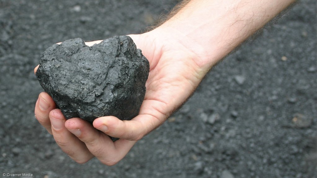 Image shows a hand holding coal 