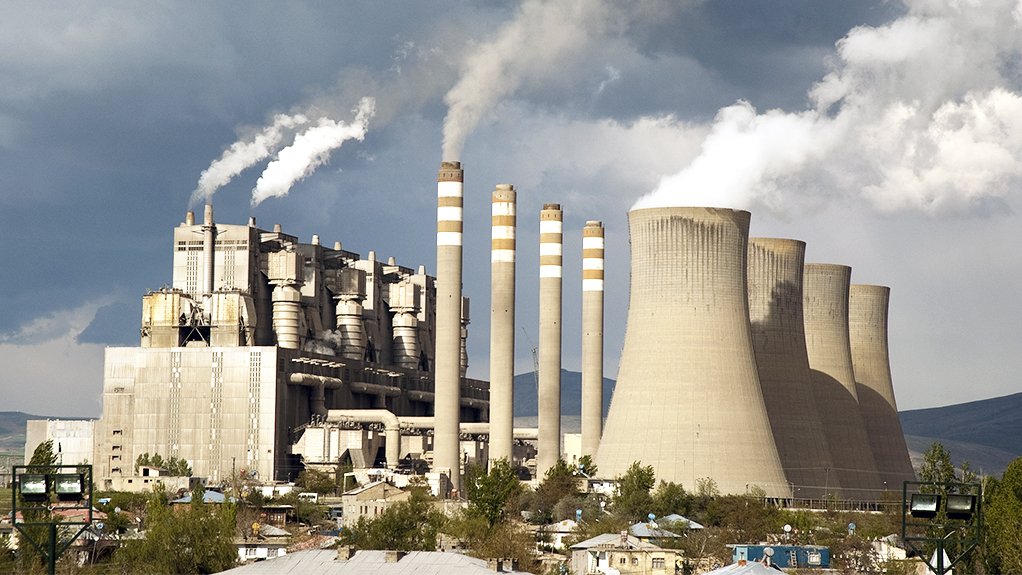 the cooling towers and stacks with smoke pluming out the top