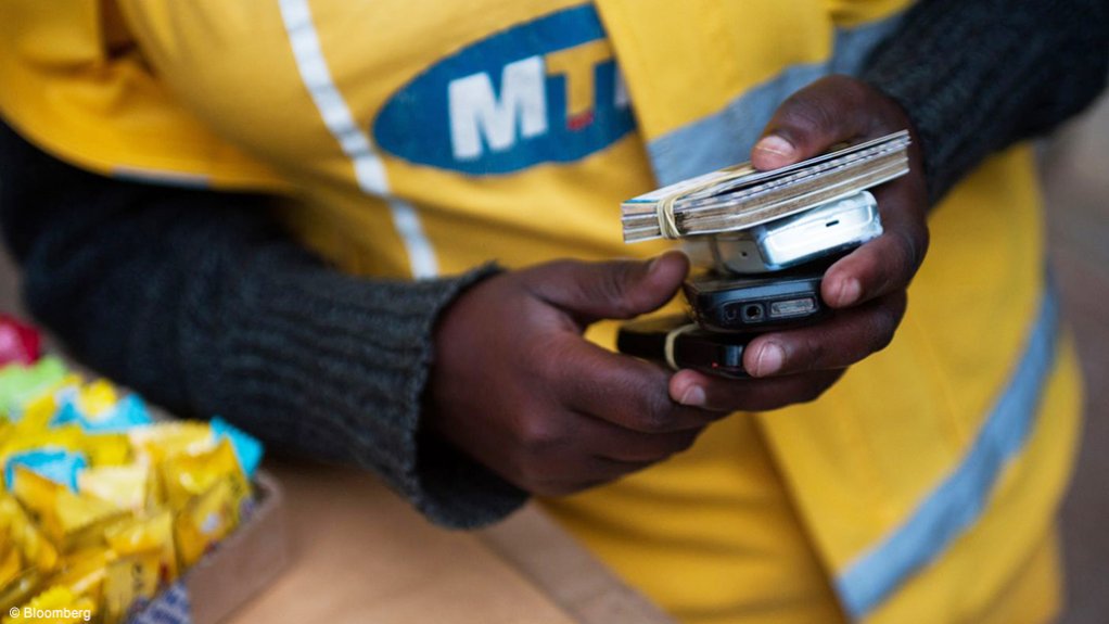 Image of a person in an MTN short holding cards and mobile phones