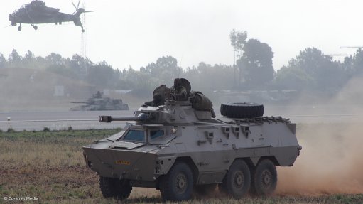 A Rooivalk aircraft flying above a Ratel vehicle