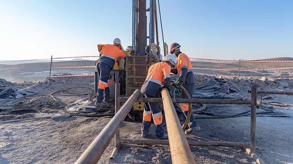 Three men in PPE at a core sampling drill near the Brandberg West mine, in the Erongo region 