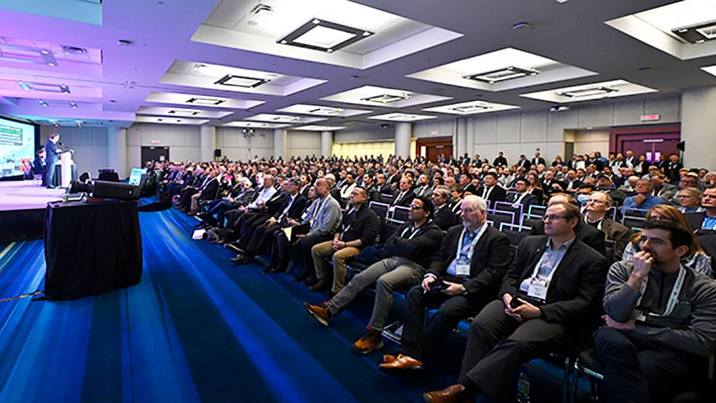A large group of delegates in a blue light in front of a stage at the PDAC
