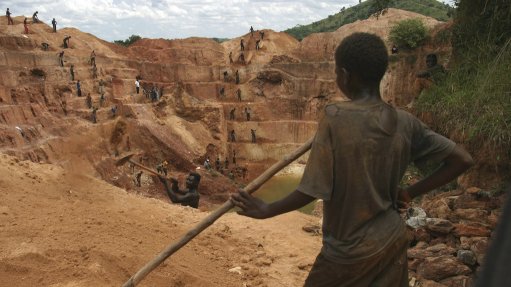  A young boy miner stood in front of an openpit artisanal mine in the Democratic Republic of Congo