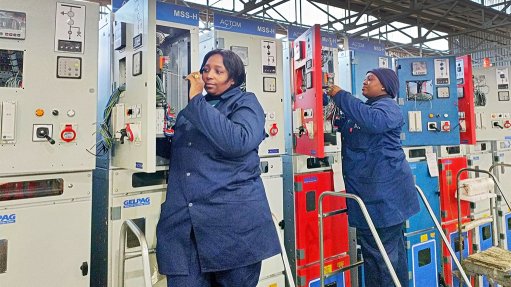 Two ladies working on a group of electrical switchgear units