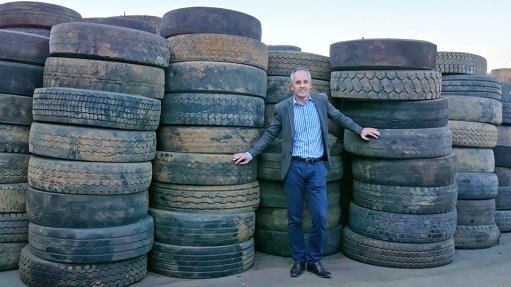 An image of Dr Mehran Zarrebini posing in front of waste tires