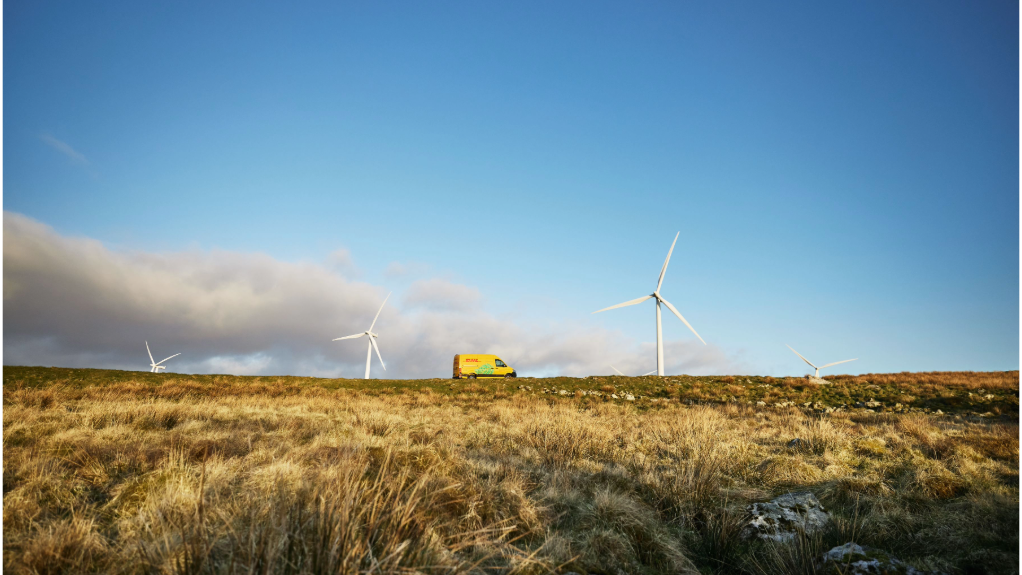 An image of wind turbines at a power generation site with a DHL vehicle in the foreground 