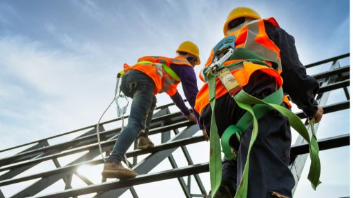 Two men on a scaffold wearing PPE and safety harnesses 