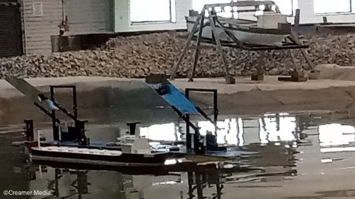 A ship mooring behaviour experiment being run in a CSIR water tank; in the background, another ship model is on the moment-of-inertia calibration cradle  