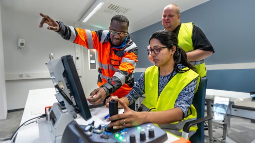 image of people around a computer to show Simulation equipment used in Sandvik Mining and Rock Solutions training