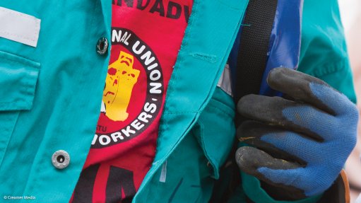 A mineworker wearing an NUM T-shirt and overalls