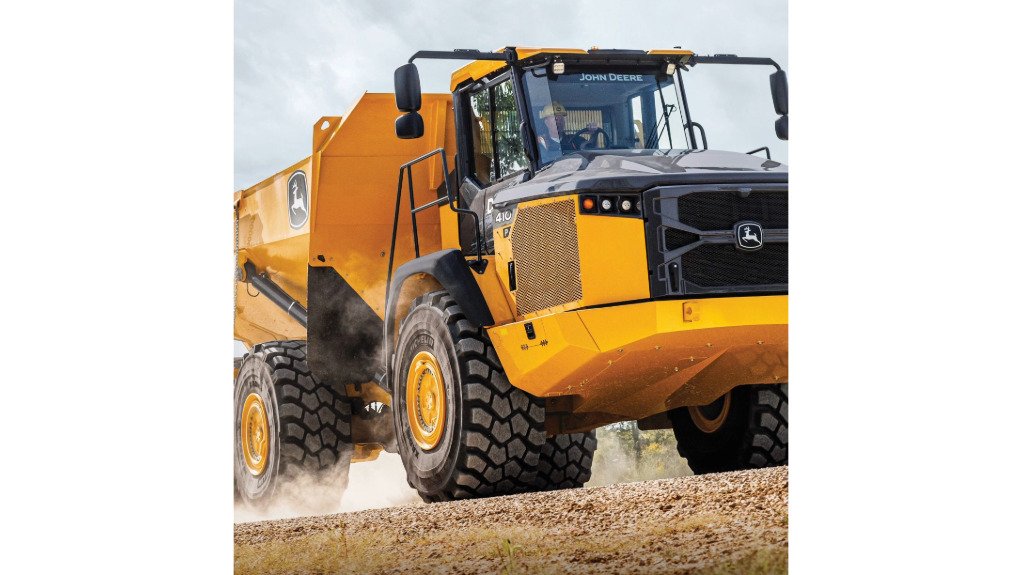 A large yellow 410 P-Tier Articulated Dump Truck with a man wearing PPE driving it