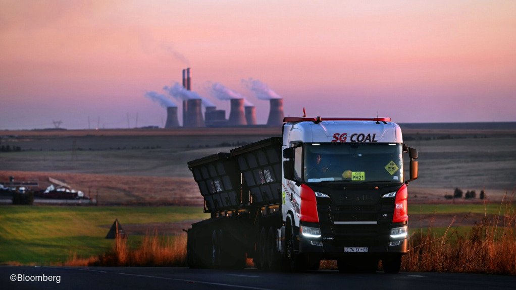A truck transporting coal, with a power station in the background