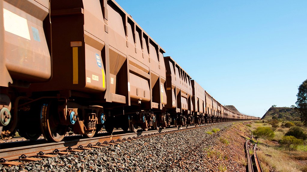 An iron ore train on tracks covered in ore dust