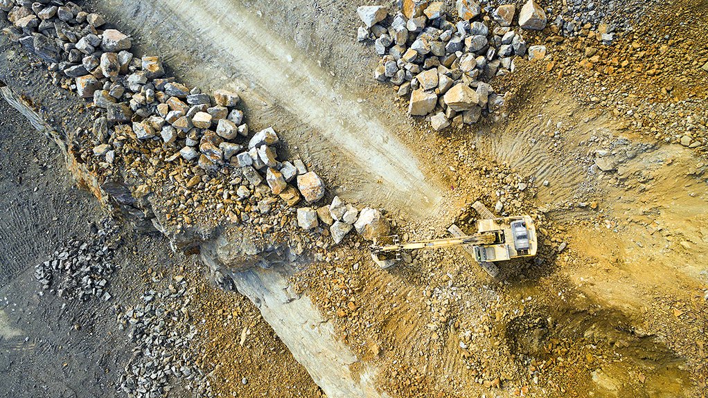 An image of a surface mining site being worked by an excavator 