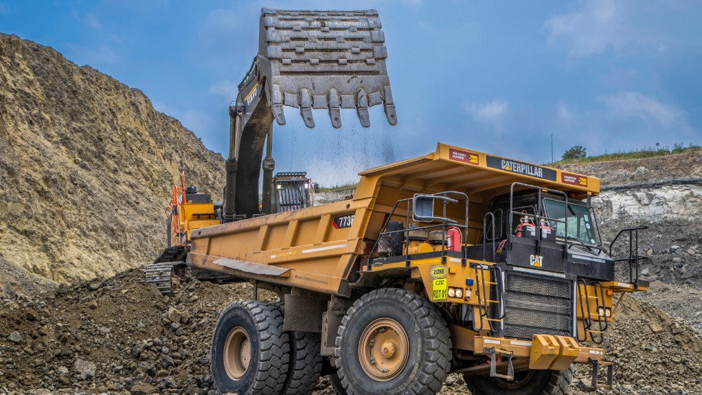 A large yellow Truck being loaded by a large scoop on an opencast mining operation