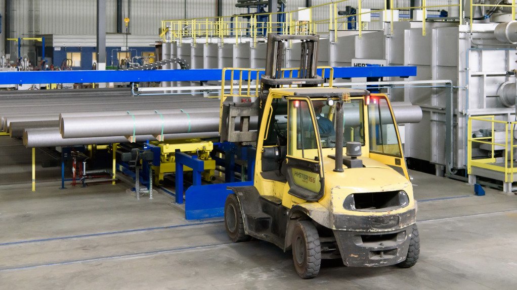 A large forklift loading large aluminium rolls to a plant