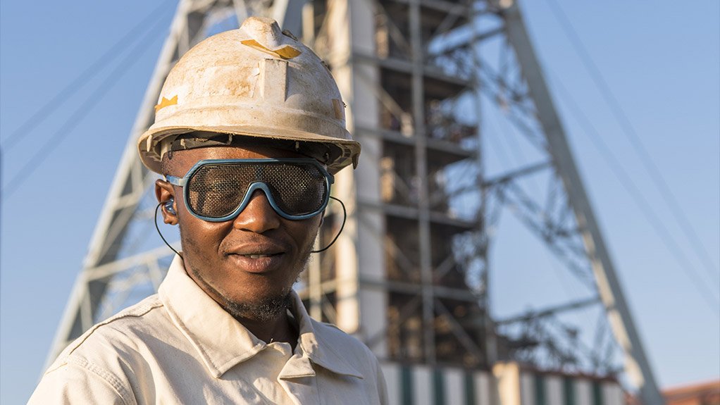 An employee at a gold mine wearing goggles and earplugs