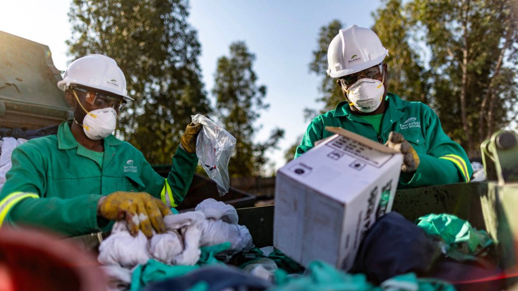 A man and woman, in EnviroServ attire and PPE sorting through waste at one of its sites