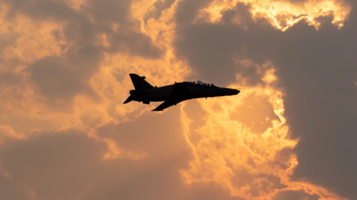 An image of a fighter jet flying during sunset