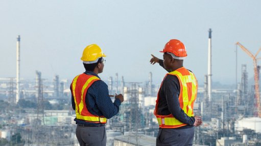 Two men in PPE standing on top of a building looking away and pointing to the horizon 