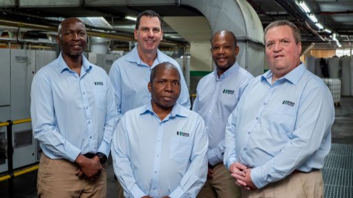 A photo of Beier group executives stood together in a factory in branded corporate clothing