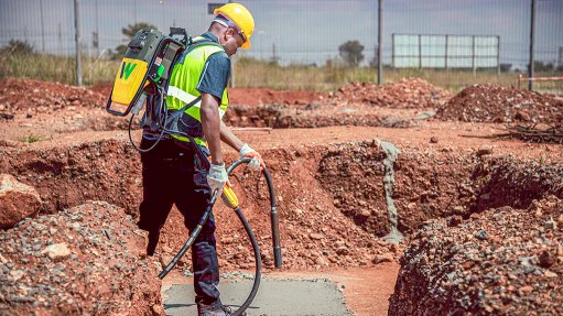 Image of a worker laying concrete on a road, using backpack internal vibrator from Wacker Neuson