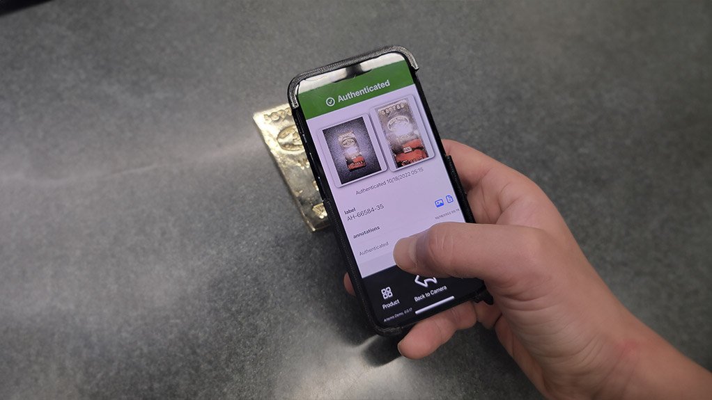 An image of a person using a cellphone and Alitehon's patented software to verify a gold bar