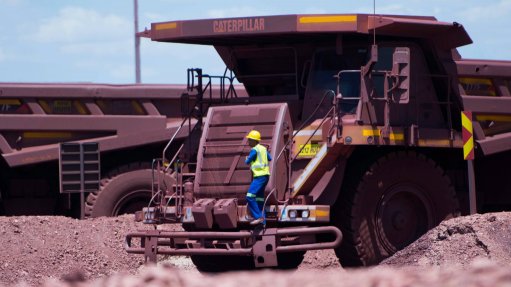 A worker wearing full PPE climbing down a LDH truck at teh Kolomela mine owned by Kumba