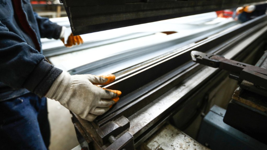 A man wearing PPE and Gloves cutting sheet steel for SteelTech in Edenvale