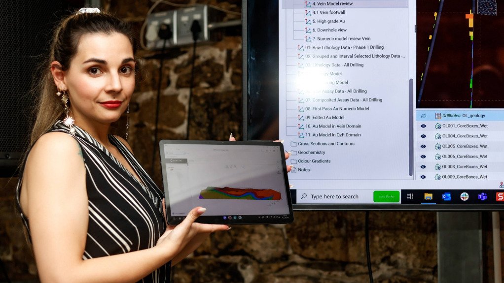 A Seequent representative displaying a laptop loaded with Seequents mining Technology which projects to a large screen