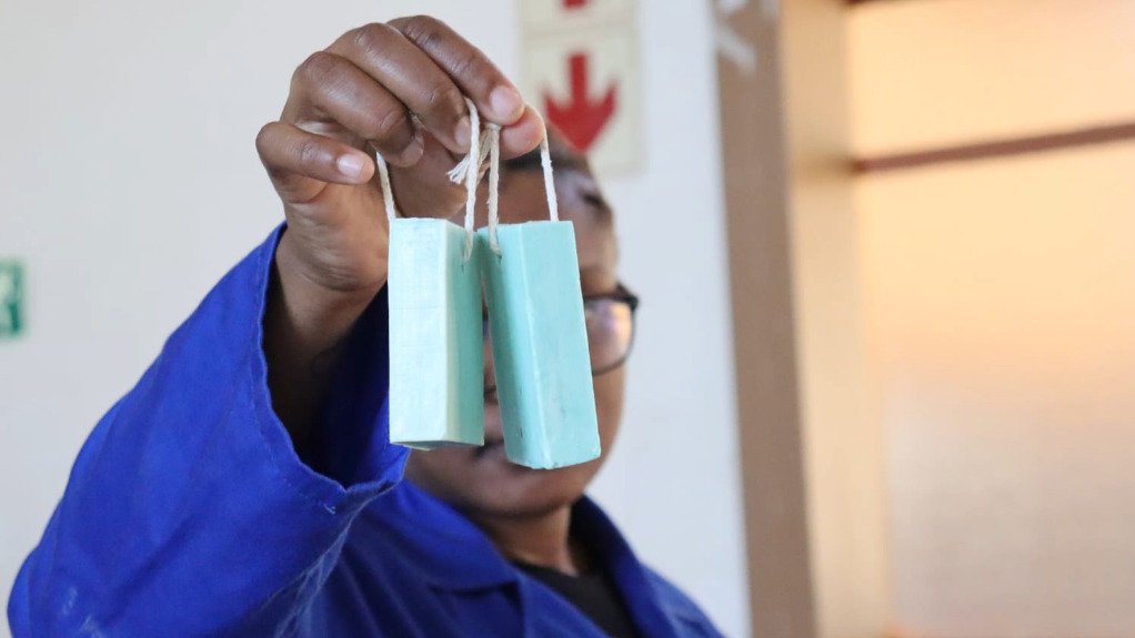 A woman holding up two bars of soap on a string